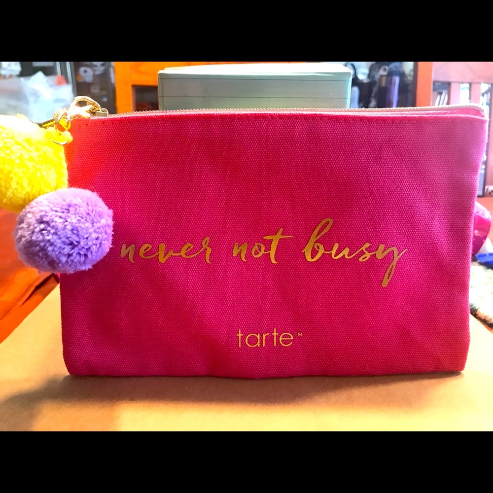New. No tags. Tarte Canvas Cosmetic Bag in Pink w/yellow and purple Pom Poms.